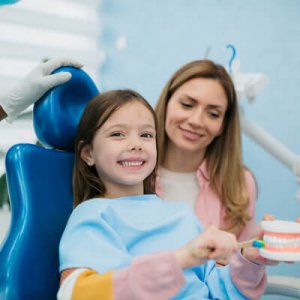 girl brushing model teeth at  dentist
