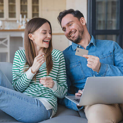 smiling-man-and-woman-sitting-on-couch-with-laptop-sq