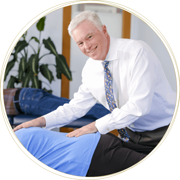 Integrative Chiropractic Doctor smiling while adjusting patient