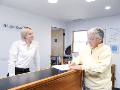 patient signing form at reception desk