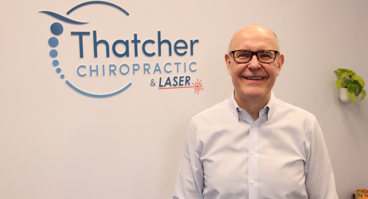 Dr. Bill standing next to Thatcher Chiropractic & Laser signage