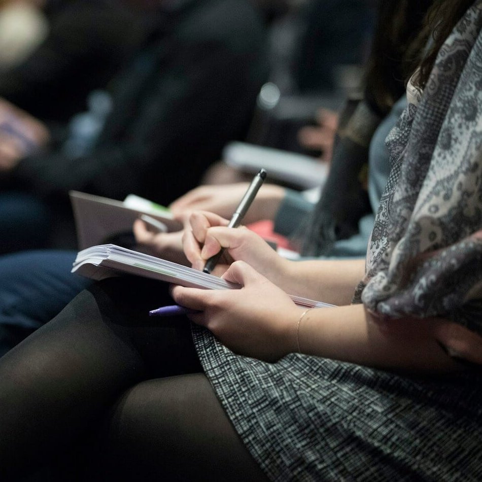 people sitting on chairs while writing on notebooks