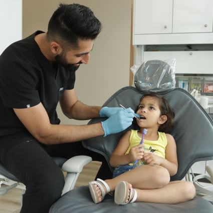 Dr. Paul checking little girls teeth