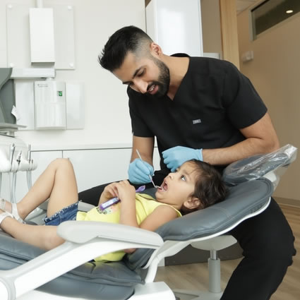 Dr. Paul checking little girls teeth