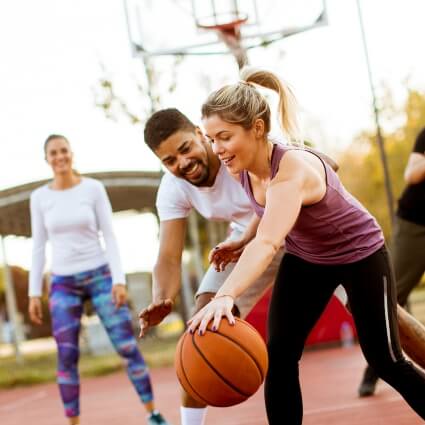 men and woman playing basketball outdoors
