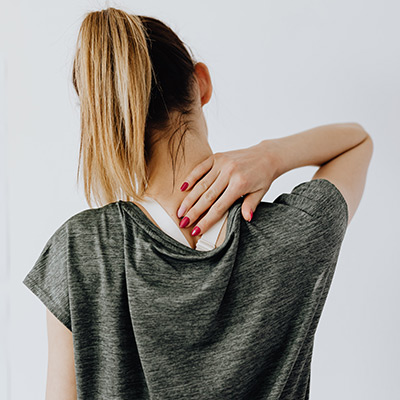woman in grey tshirt rubbing her neck in pain