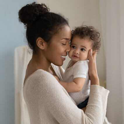 mom smiles and holds baby close face to face