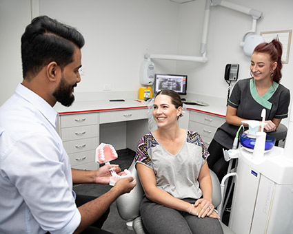 Dentist holding teeth model by patient