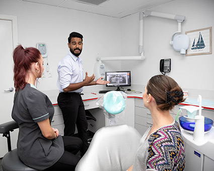 Dentist pointing to xray with patient