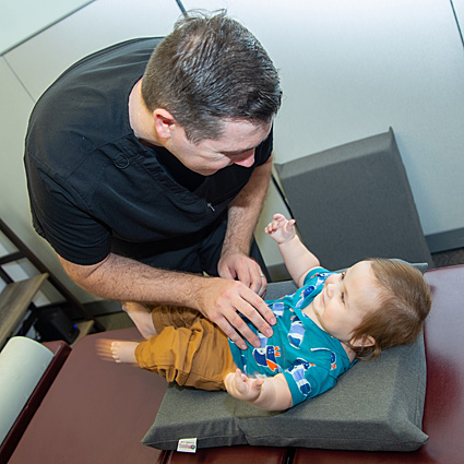 Dr. Nicholas Kirton adjusting a smiling toddler