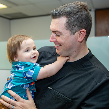 Dr. Nicholas Kirton holding a baby and smiling
