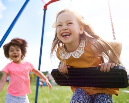 Happy girls playing on a swing