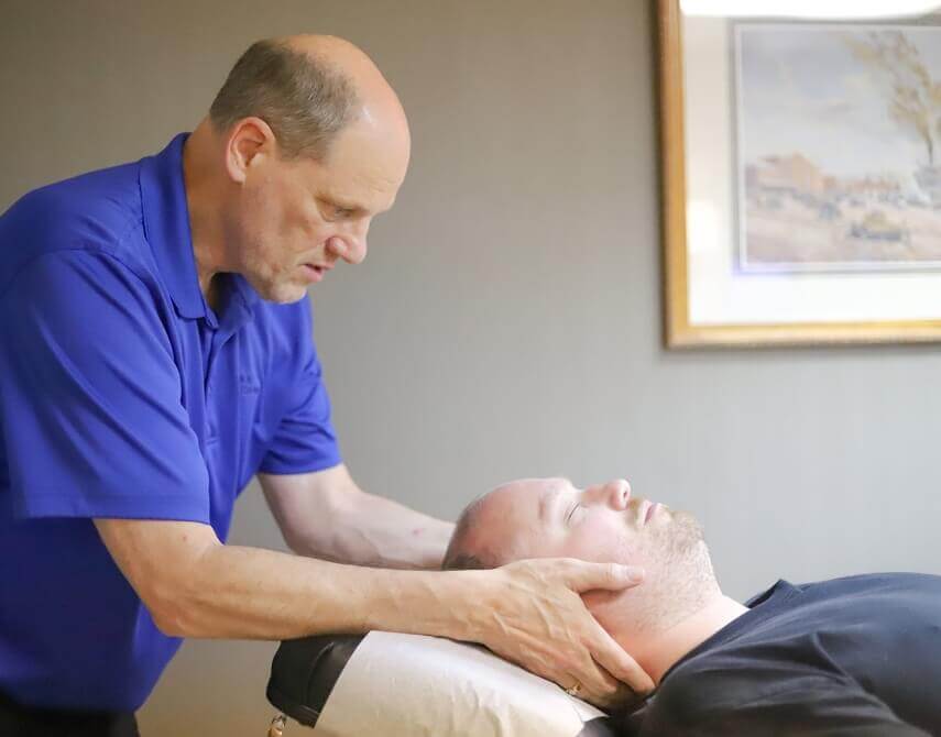 Inver Grove Heights chiropractor Dr. Scott Stinson adjusting male patient's neck