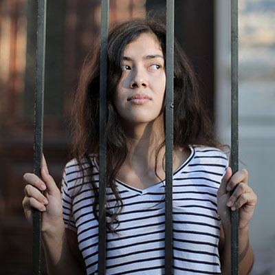 woman looking through fence bars