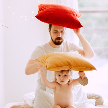 dad and child playing pillows