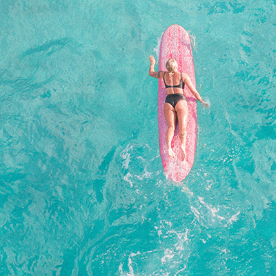 Woman surfboarding on bright blue water