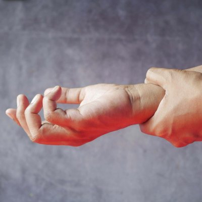 Close-up of hands, one grasping the other, symbolizing pain or discomfort.