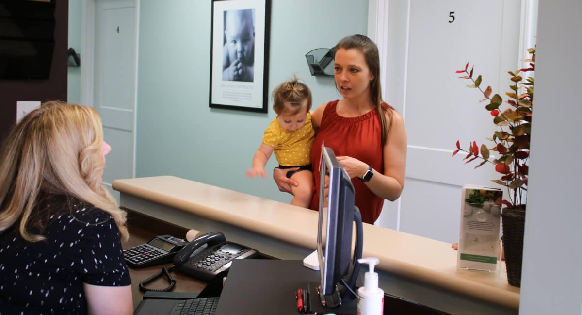 Mom and young child talking to Dickinson Chiropractic & Acupuncture receptionist