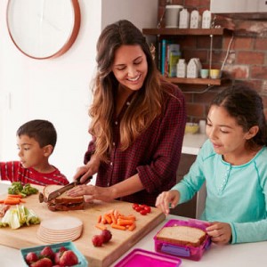 happy mom helping her two kids pack lunches