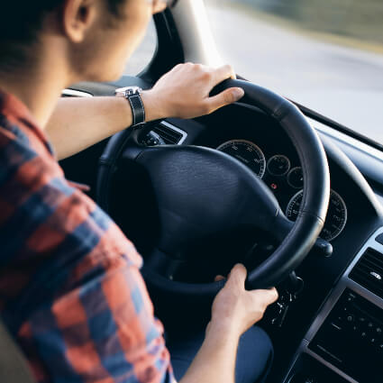 person with hands on car steering wheel