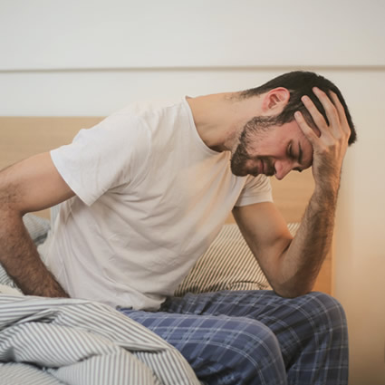 man with headache on bed
