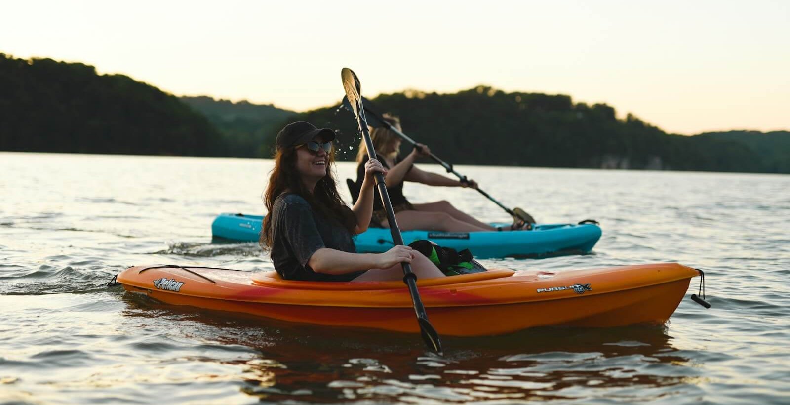 woman in blue shirt and blue denim jeans riding orange kayak on water during daytime