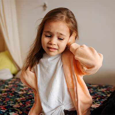 Young girl holding her ear with a pained expression