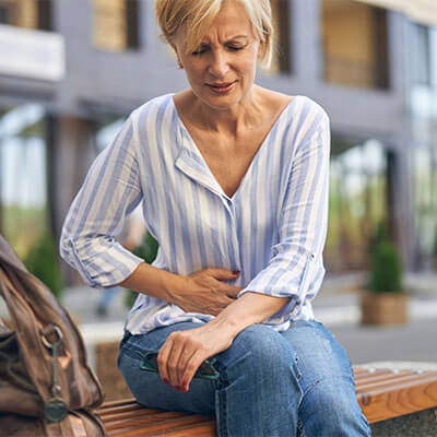 Lady sitting on bench with stomach pain