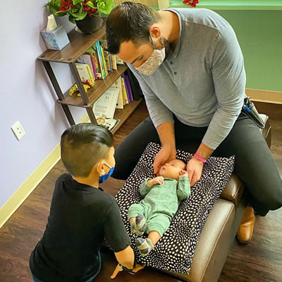 Dr Joe adjusting infant brother overlooking adjustment