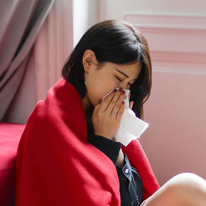 sick woman sneezing into tissue