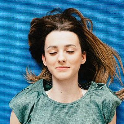 person smiling and laying down on a yoga mat