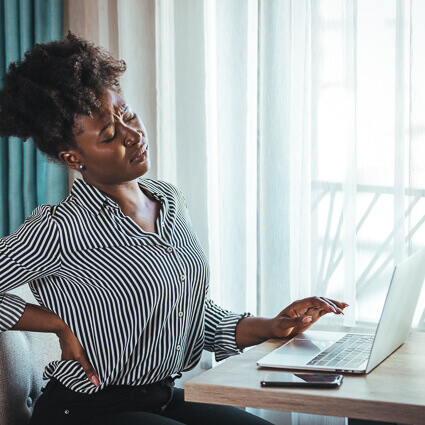 woman-in-blouse-working-at-laptop-back-pain-sq