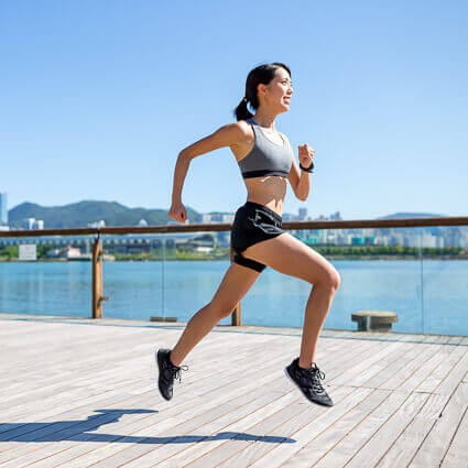 woman sprinting down pier along water 