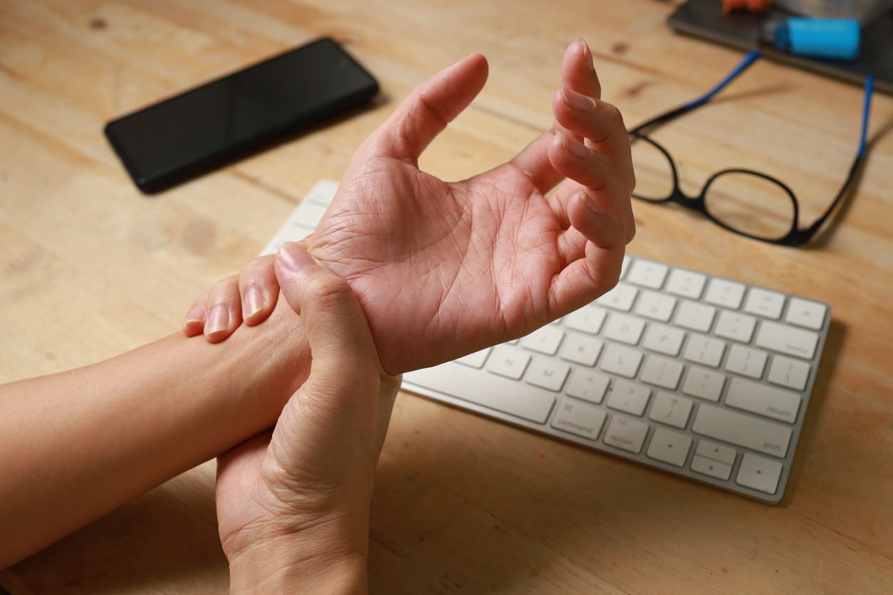 Woman suffering from wrist pain, numbness, or Carpal tunnel syndrome hand holding her ache joint while working in front computer