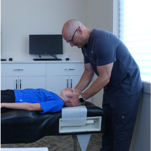 Chiropractor adjusting pediatric patient's neck