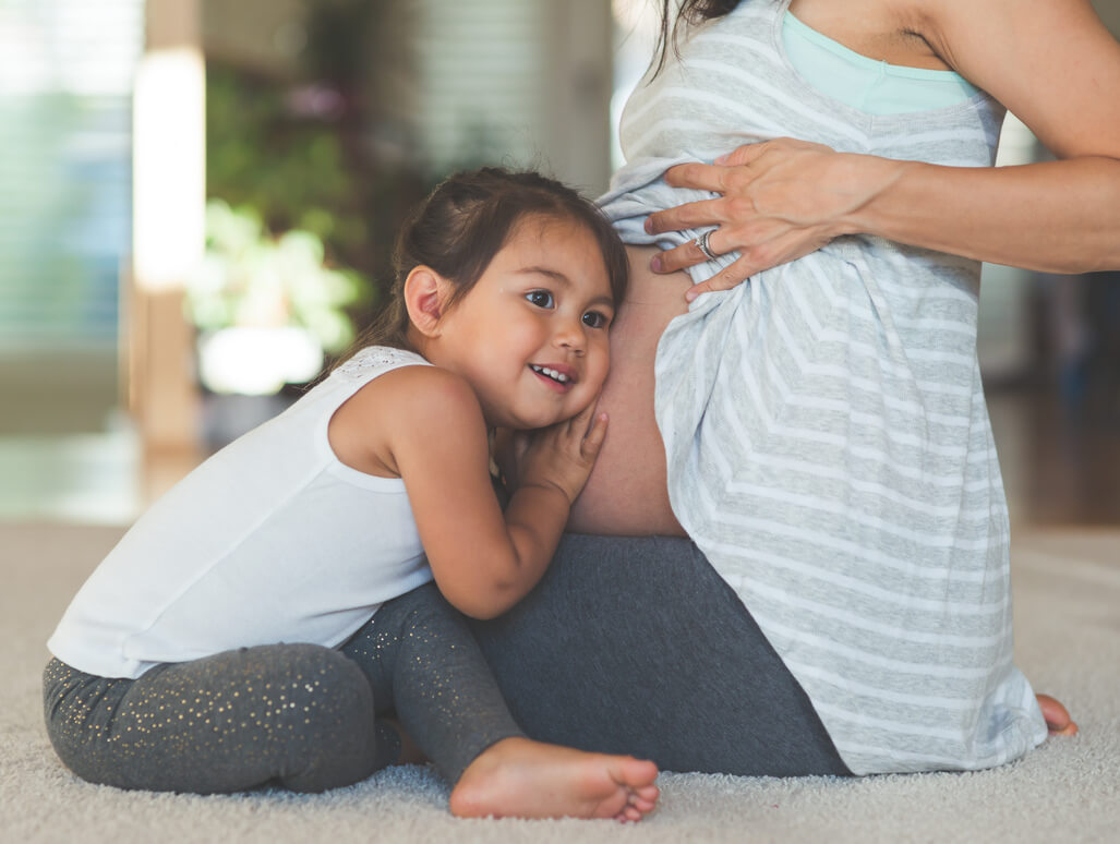 girl holding pregnant mom tummy