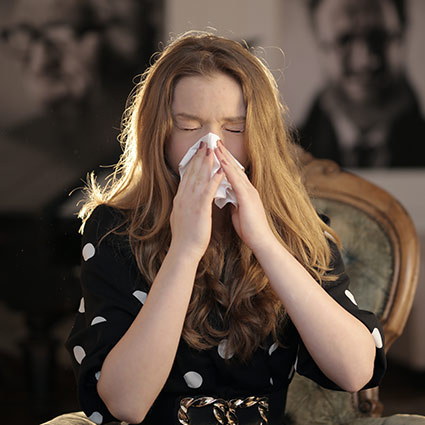 woman sneezing in to a tissue