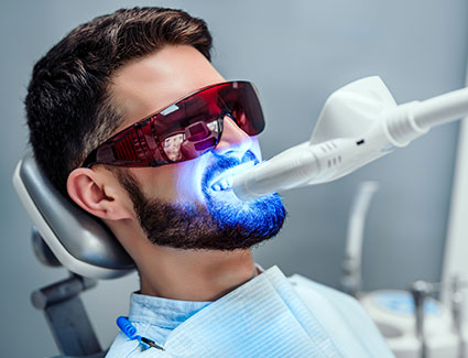 Man getting teeth whitened in office