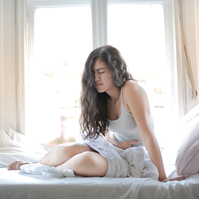 Woman sitting on a bed with stomach pain