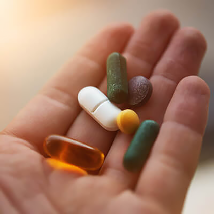 person holding supplement pills in their palm