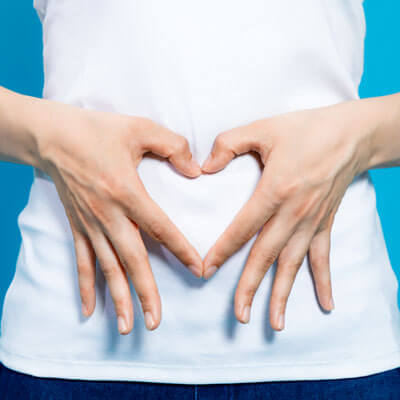 person making a heart shape with their hands on their stomach