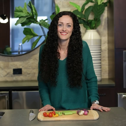 Gabrielle standing with veggies and cutting board