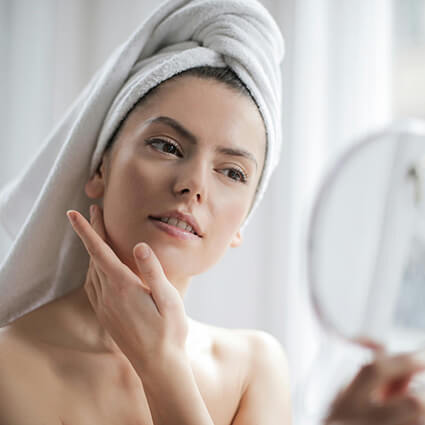 person looking at their face in a hand mirror