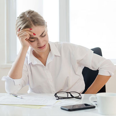 office girl sitting on chair wearing corporate attire with stomach pain