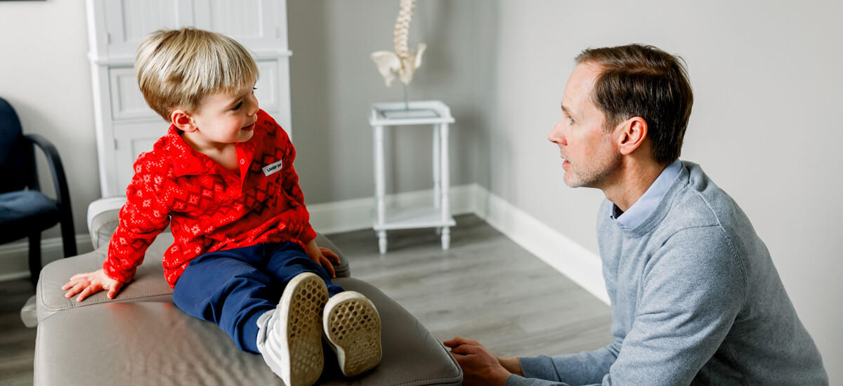 child sitting on adjusting table talking to doctor
