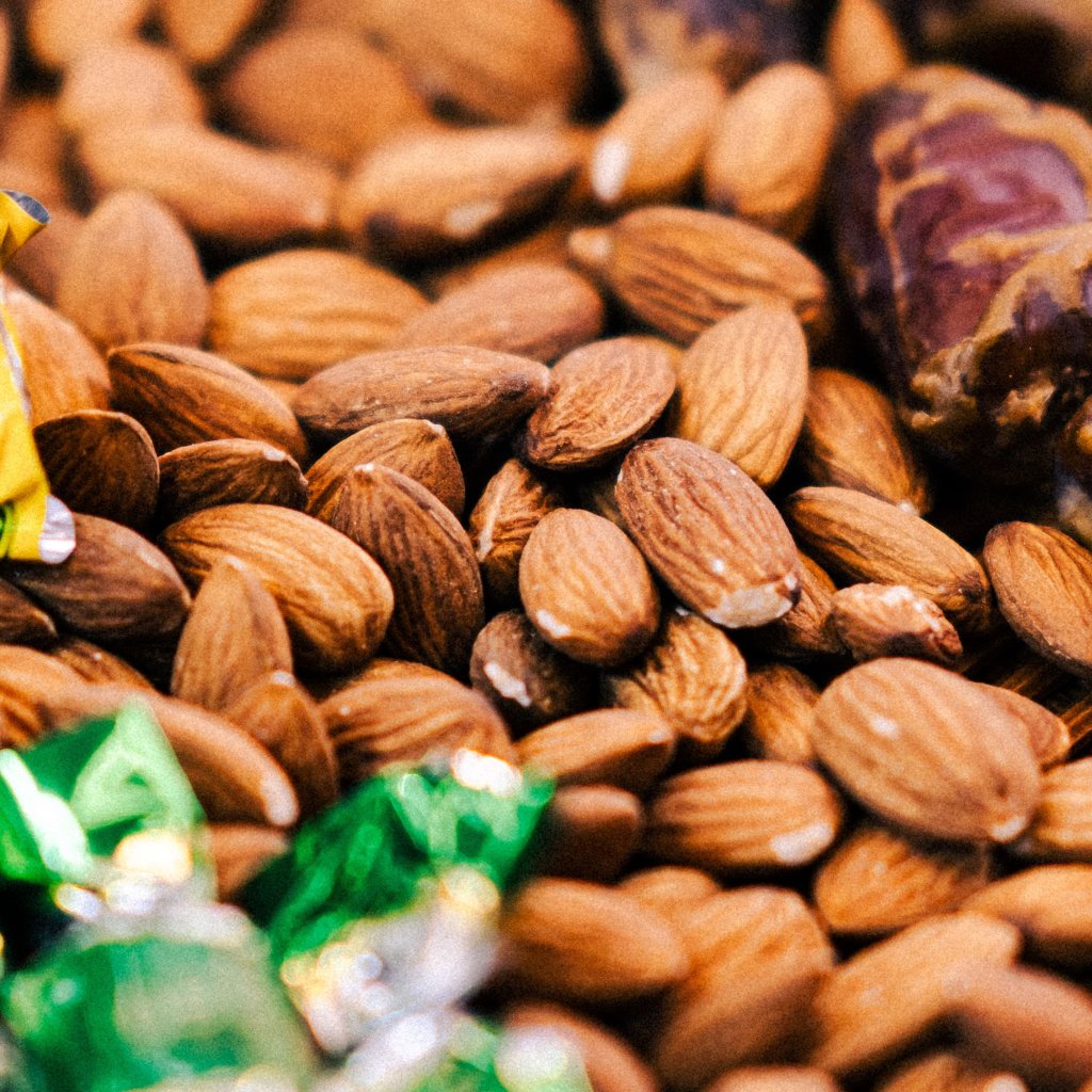 A detailed close-up shot of almonds scattered with colorful wrapped candies.