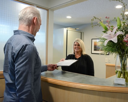 Patient handing forms to receptionist