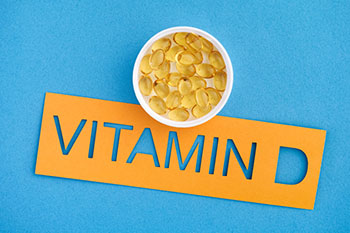 The word Vitamin D with a small cup of Vitamin D3 capsules on it