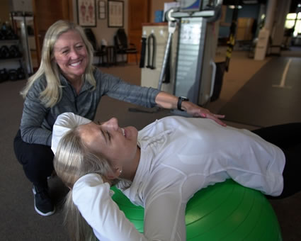 Kelly helping patient on exercise ball