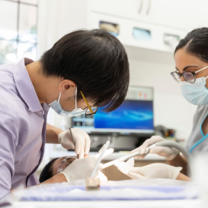 Dentist performing dental surgery with the help of assistant